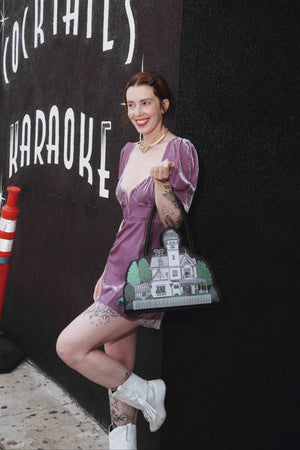 Cardboard cutout of a woman in a purple dress with a vintage-style sign in the background.